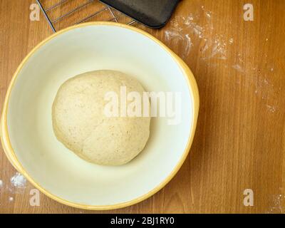 Kneaded oat bread dough in a mixing bowl ready for proving on a wooden kitchen table Stock Photo