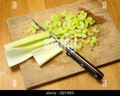 Chopping celery on a wooden chopping board on a kitchen table Stock Photo