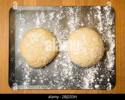 Two rounds of oat bread dough rolled in oats on a floured baking sheet on a kitchen table Stock Photo