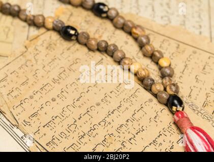 Muslim prayer beads with ancient pages from the Koran. Islamic and Muslim concepts. Ancient old sheets of paper from the Arabic book Stock Photo