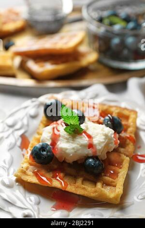 Sweet homemade waffles on plate, on color wooden background Stock Photo