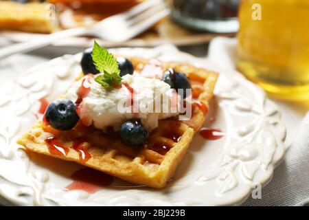 Sweet homemade waffles on plate, on color wooden background Stock Photo