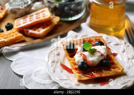 Sweet homemade waffles on plate, on color wooden background Stock Photo