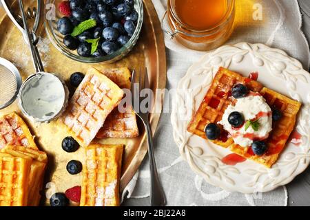 Sweet homemade waffles on plate, on color wooden background Stock Photo