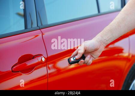 Male hand pressing alarm button of red car Stock Photo