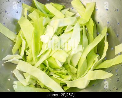 Washed fresh pointed cabbage slices in a stainless steel colander Stock Photo