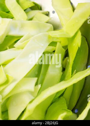 Washed fresh pointed cabbage slices in a stainless steel colander Stock Photo