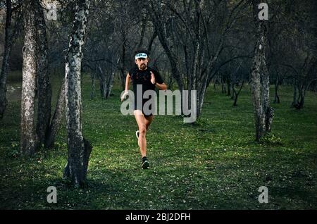 Fit man with beard running fast on the forest Stock Photo