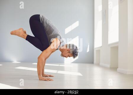 Yoga man. A man is practicing yoga balance in a gray room. Stock Photo
