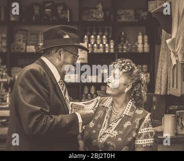 Sepia photo of 1940s spiv doing a deal with shopkeeper in WW2 grocery shop, 1940s WWII summer event. Stock Photo
