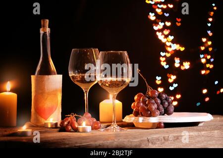 Wine glass near bottle on hearts bokeh background Stock Photo