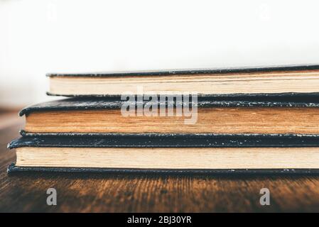 close-up shot of stack of vintage books on rustic wooden table Stock Photo