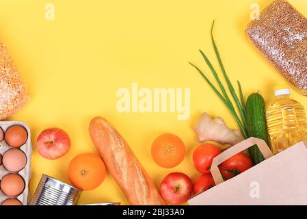 Paper bag with food supplies for the period of quarantine isolation on a yellow background. Food delivery, donation, coronavirus. Copyspace. Buckwheat Stock Photo