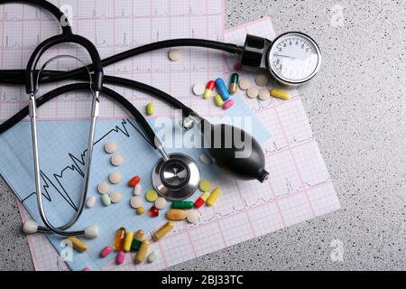 Blood pressure meter, pills and stethoscope, on grey background Stock Photo