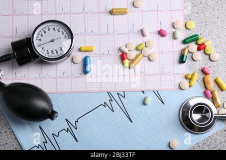 Blood pressure meter, pills and stethoscope, on grey background Stock Photo