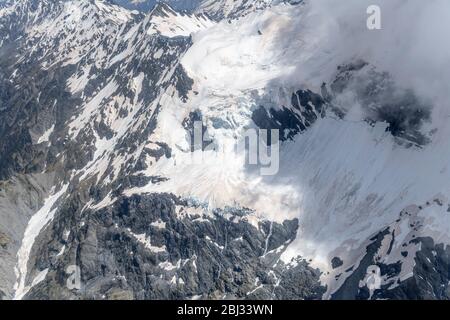 aerial, from a glider, with snow landslides and clouds wisps at Selwyn glacier, shot in bright spring light from north-east, Canterbury, South Island, Stock Photo