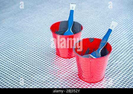 Close up of paint brushes in paint buckets outside. Home renovation Stock Photo