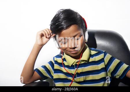 Boy with headphone  sitting on Chair enjoying music Stock Photo