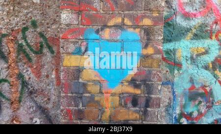 A crumbling abandoned building with three different textures on its old walls and a painted graffiti heart on the chimney bricks Stock Photo