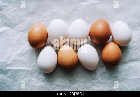 Brown and white uncooked farm chicken eggs on white paper Stock Photo