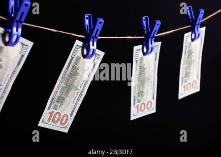 Concept of money laundering - one hundred bills hanging on a cord against grey background Stock Photo