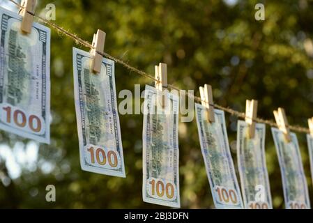Concept of money laundering - one hundred bills hanging on a cord, outdoors Stock Photo