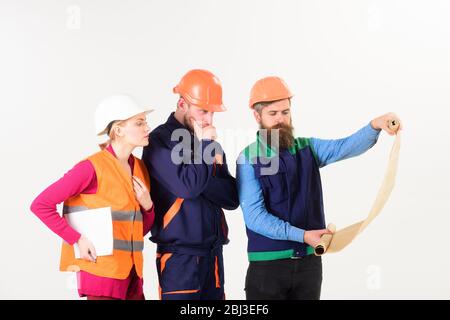 Team of builder, engineer, architect work on project. Engineering concept. Men and woman in helmets, architects on thoughtful faces looks at drawing, plan, blueprint, project, white background. Stock Photo