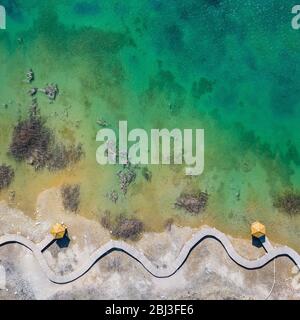 Aerial view of wooden path over turquiose lake colour. Drought. Drone top view. Stock Photo