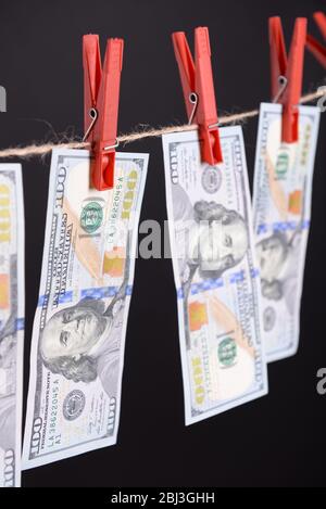Concept of money laundering - dollars are drying on red clips on cord on black background Stock Photo