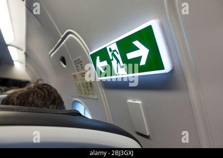 Aircraft emergency exit sign and door on board passenger airplane Stock Photo