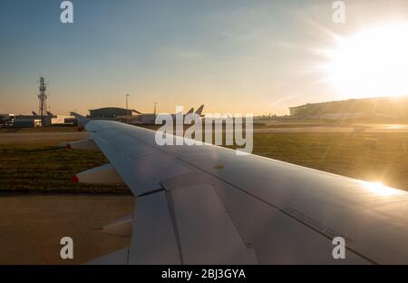 HEATHROW AIRPORT, LONDON, ENGLAND – January 20 2019, view across the wing of a British Airways aircraft landing and airplanes waiting at sunset, Termi Stock Photo