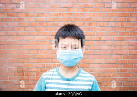 Asian boy wearing a mask background brick wall. Stock Photo