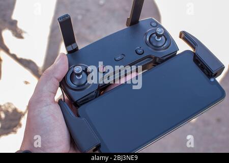 Hand holding drone remote controler to operate flying drone on a sunny day Stock Photo