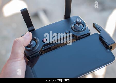 Hand holding drone remote controler to operate flying drone on a sunny day Stock Photo