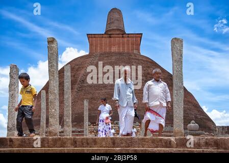 Anuradhapura, Sri Lanka - August 16, 2017: Pilgrims leave the Jetavanaramaya stupa after prayers. A stupa is a Buddhist reliquary monument Stock Photo