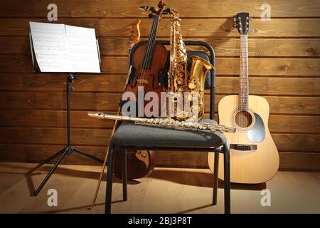 Musical instruments on a chair and note holder against wooden ...