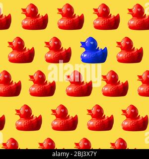 Lots of red plastic ducks with one blue duck on a yellow background Stock Photo