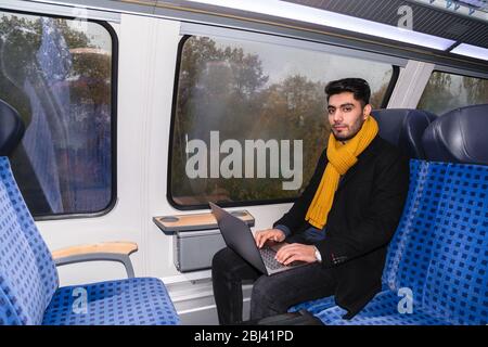 Man with laptop sits near window in train journey Stock Photo