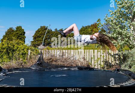 Camptoun, East Lothian, Scotland, United Kingdom. 28th Apr, 2020. A community in lockdown: residents in a small rural community show what life in lockdown is like for them. Pictured: Louisa aged 11 years in P7. Her home schooling includes PE exercises on a trampoline Stock Photo