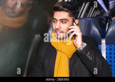 Businessman commuting to work on train using phone Stock Photo