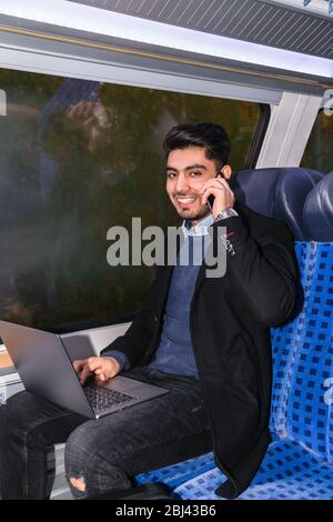 Fashionable guy with laptop and phone in train Stock Photo