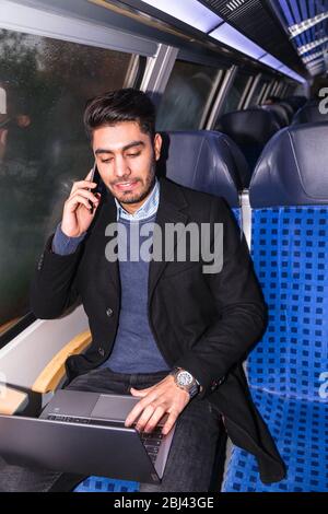 Businessman working with laptop on way in train Stock Photo
