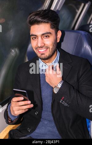 Man sits in train with notebook and phone in hand Stock Photo