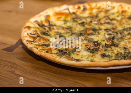 Pizza with mushrooms and cheese is sprinkled with dry Italian herbs Stock Photo