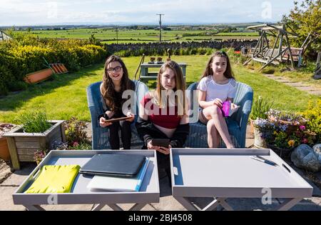 Camptoun, East Lothian, Scotland, United Kingdom. 28th Apr, 2020. A community in lockdown: residents in a small rural community show what life in lockdown is like for them. Pictured (L to R): Imogen, Eva and Louisa. Imogen and Louisa are twins aged 11 years in P7. They may miss the normal transition to high school. Eva is in S2 and 13 years old. They are home schooling Stock Photo