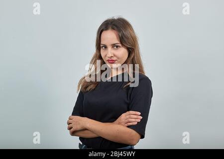 woman in black t-shirt on gray cool girl looks confident, hands crossed Stock Photo