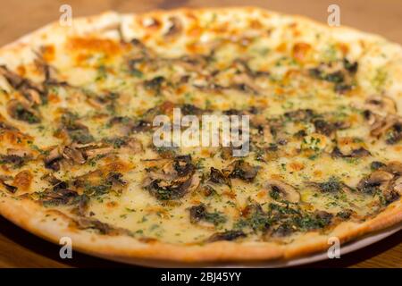 Pizza with mushrooms and cheese is sprinkled with dry Italian herbs Stock Photo