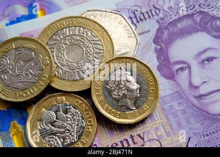 New polymer 20 pounds note with pile of pound coins placed on top. Close up photo. Concept for personal finance. Stock Photo