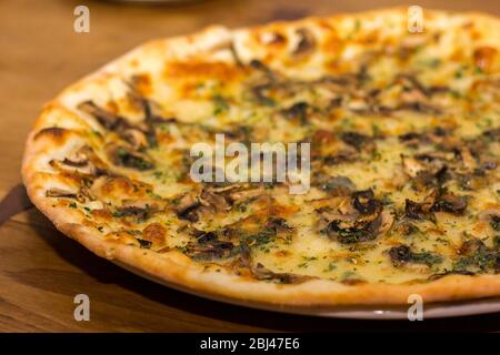 Pizza with mushrooms and cheese is sprinkled with dry Italian herbs Stock Photo