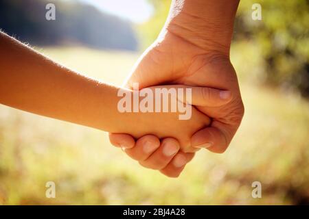 A parent holds the hand of a small child Stock Photo